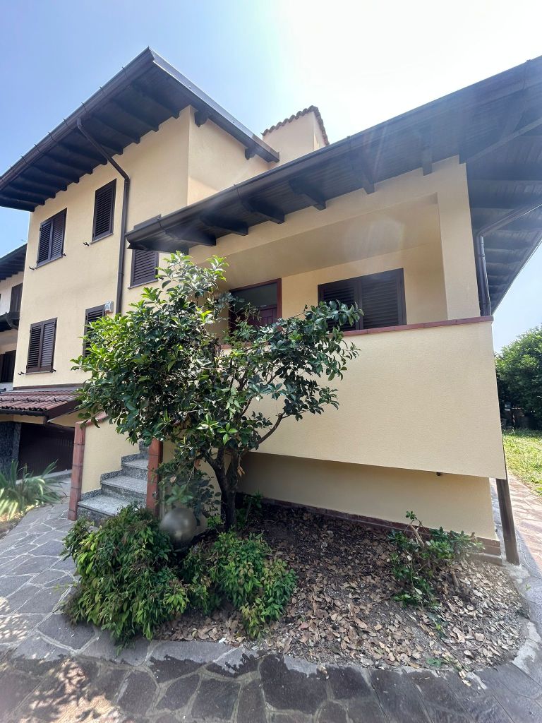 Vista esterna di un edificio residenziale con facciata gialla e tetto in legno, circondato da vegetazione e un sentiero in pietra.