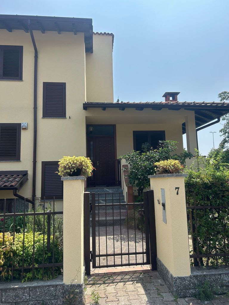 Facciata di una casa con portone d'ingresso e giardino, vista da fuori.