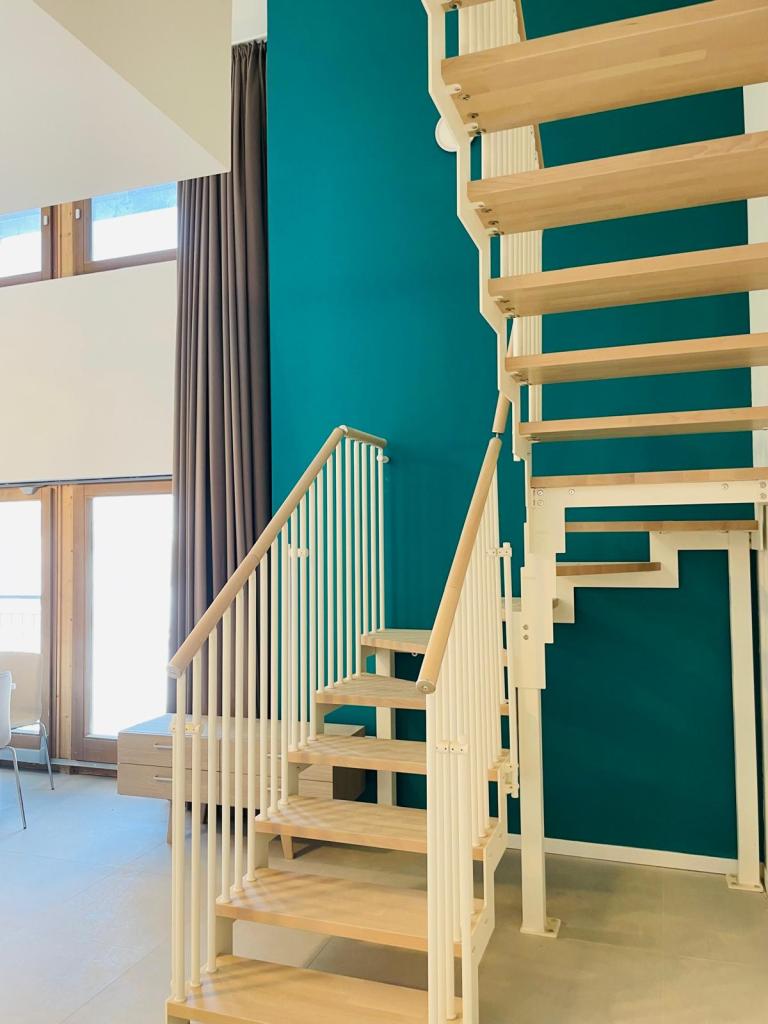Scala in legno con ringhiera bianca in un ambiente moderno con parete verde acqua.